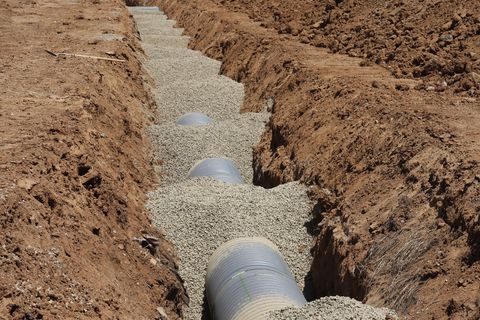 A drainage pipe bedded in gravel in an open trench