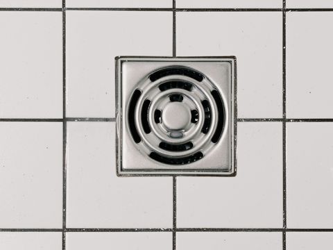 A square stainless floor waste in a tiled floor