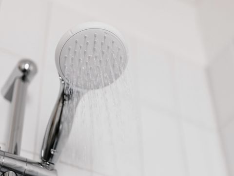 A hand shower running against white tiles
