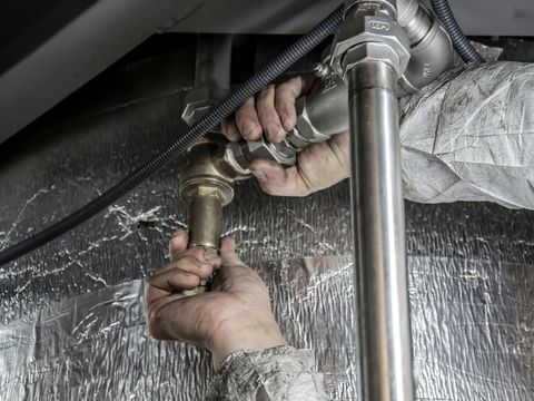 Hands tightening brass fittings on water pipes